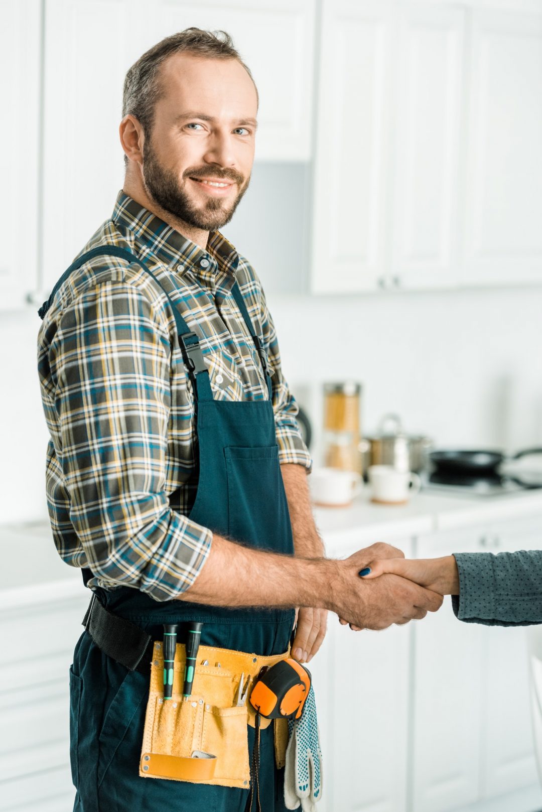 smiling handsome plumber and customer shaking hands in kitchen 1